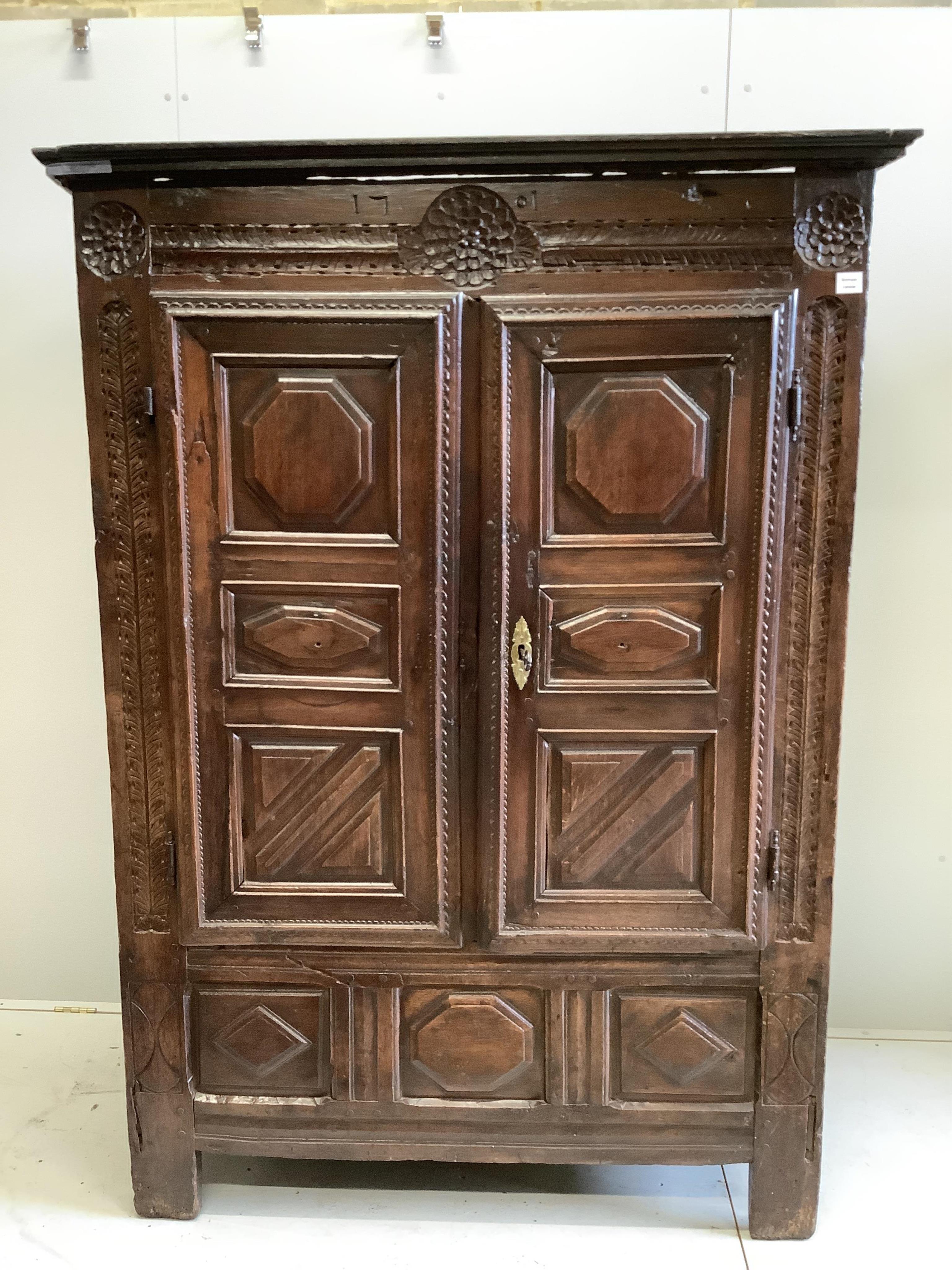 An early 18th century continental panelled oak cupboard bearing date 1701, width 130cm, height 193cm. Condition - fair, cornice detached, lacks inner shelves